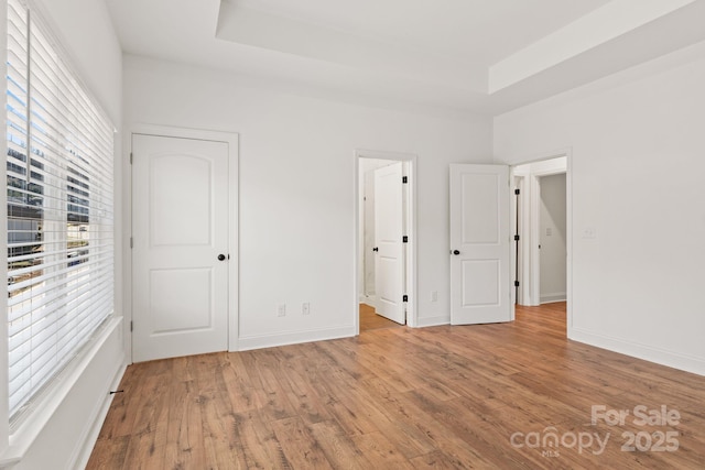 unfurnished bedroom with hardwood / wood-style floors and a raised ceiling