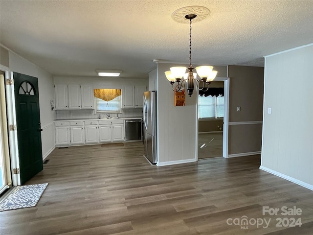 kitchen featuring appliances with stainless steel finishes, dark hardwood / wood-style flooring, pendant lighting, white cabinets, and a chandelier