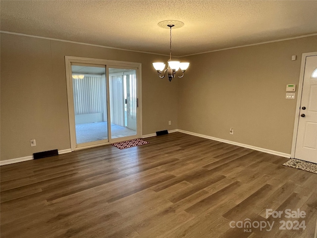 interior space with a chandelier, dark wood-type flooring, a textured ceiling, and ornamental molding