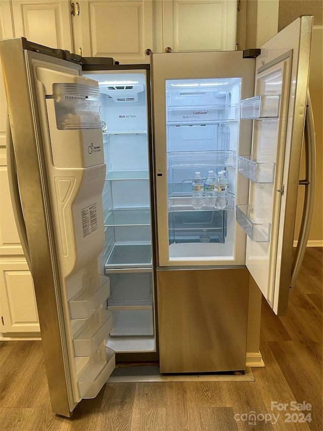 interior space with stainless steel fridge, white cabinetry, and light hardwood / wood-style flooring