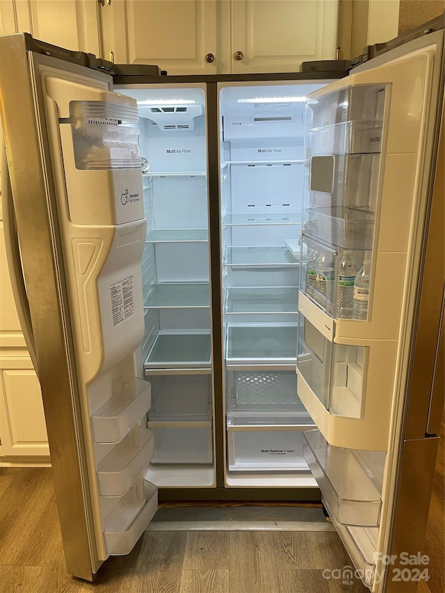 room details with stainless steel refrigerator and hardwood / wood-style flooring