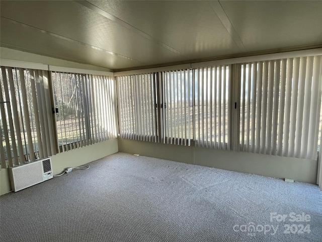 unfurnished sunroom featuring lofted ceiling and a wall mounted air conditioner