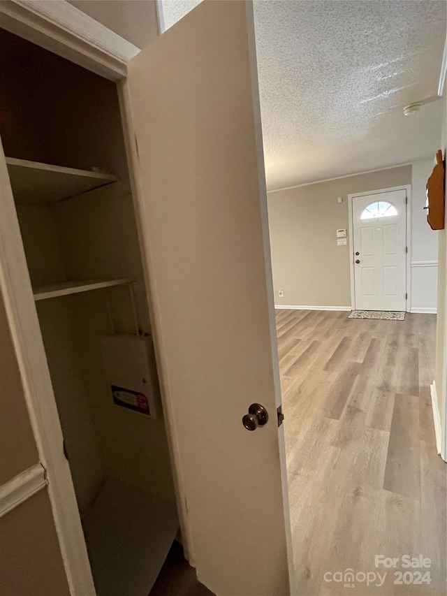 foyer entrance with a textured ceiling and light hardwood / wood-style flooring