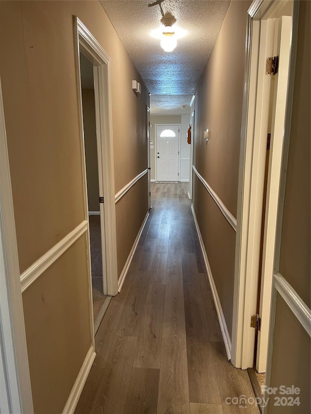 hall with a textured ceiling and dark wood-type flooring