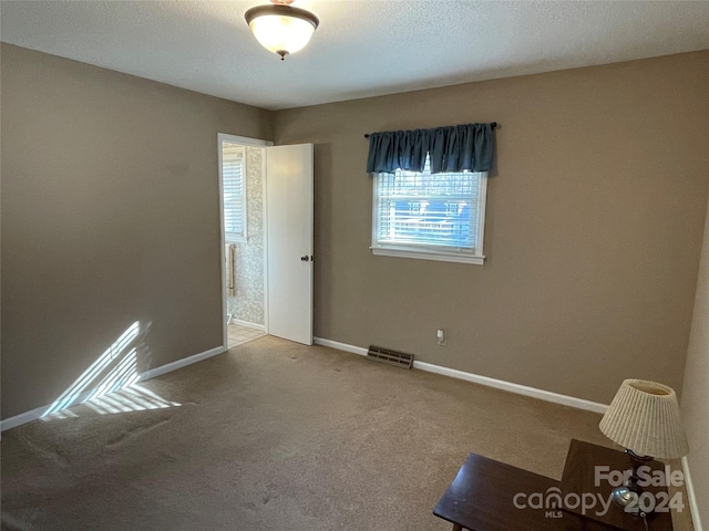 carpeted empty room with a textured ceiling