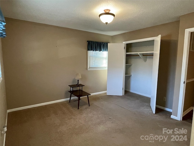 unfurnished bedroom featuring carpet floors, a textured ceiling, and a closet