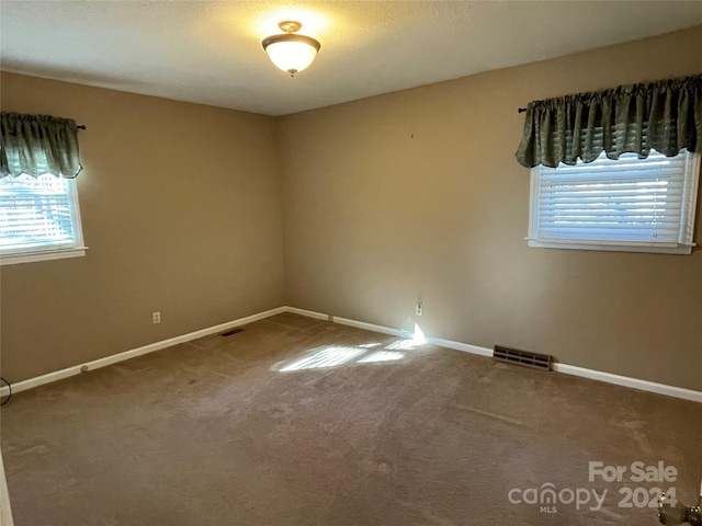 carpeted empty room featuring a textured ceiling