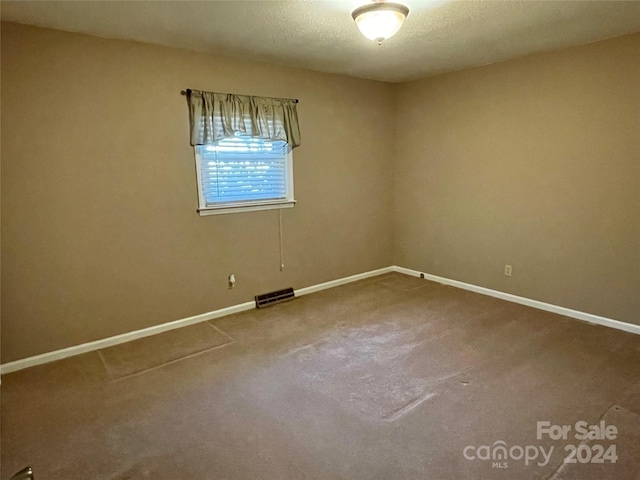 carpeted empty room with a textured ceiling