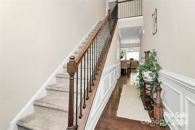 stairway featuring wood-type flooring and an inviting chandelier