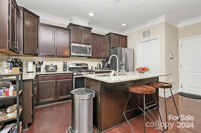 kitchen featuring light stone countertops, sink, dark wood-type flooring, a center island with sink, and appliances with stainless steel finishes