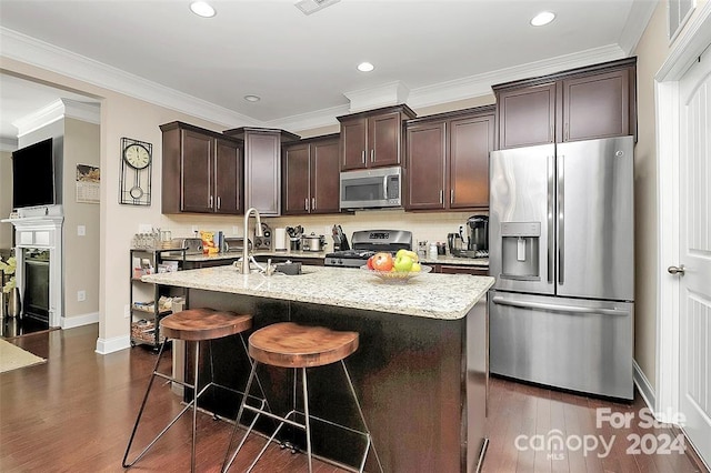 kitchen featuring appliances with stainless steel finishes, dark hardwood / wood-style floors, ornamental molding, and a center island with sink