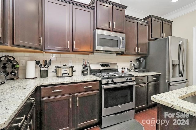 kitchen with decorative backsplash, ornamental molding, dark hardwood / wood-style flooring, light stone counters, and stainless steel appliances