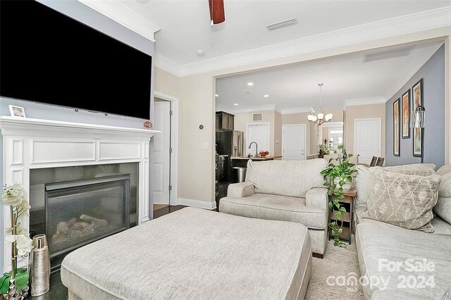 living room featuring ceiling fan with notable chandelier and ornamental molding