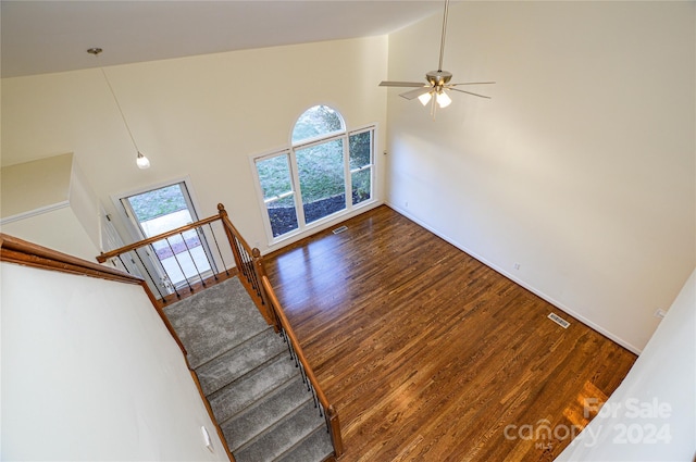 unfurnished living room with ceiling fan, plenty of natural light, dark hardwood / wood-style floors, and high vaulted ceiling