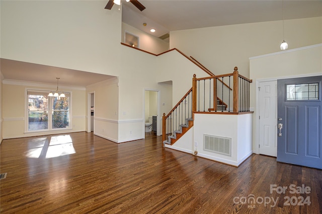 foyer featuring ceiling fan with notable chandelier, dark hardwood / wood-style floors, high vaulted ceiling, and crown molding