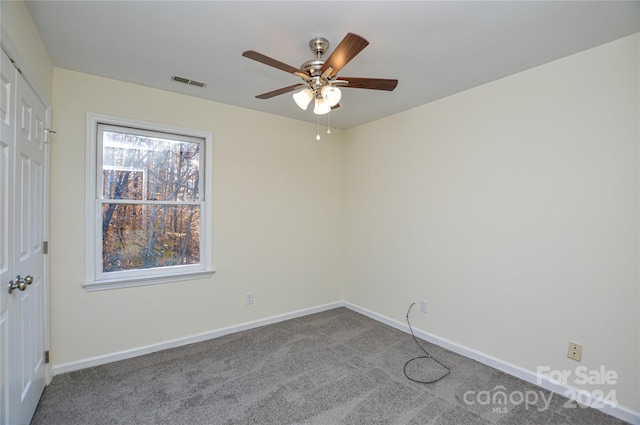 carpeted spare room featuring a wealth of natural light and ceiling fan