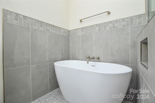 bathroom featuring tile patterned floors, a bathtub, and tile walls