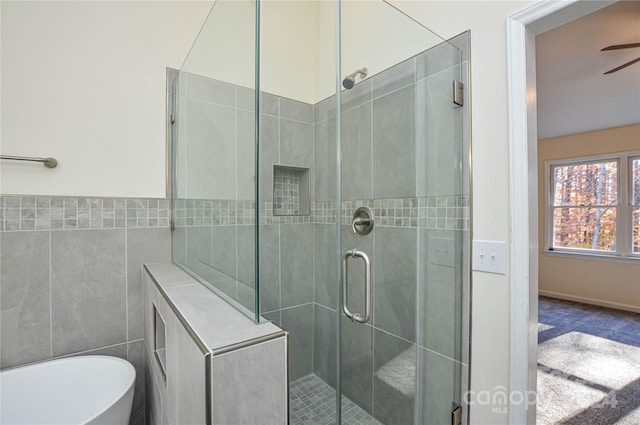 bathroom featuring ceiling fan, tile walls, and plus walk in shower