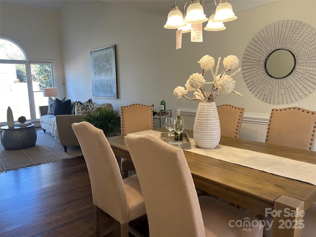 dining room with a notable chandelier, dark hardwood / wood-style floors, and a high ceiling