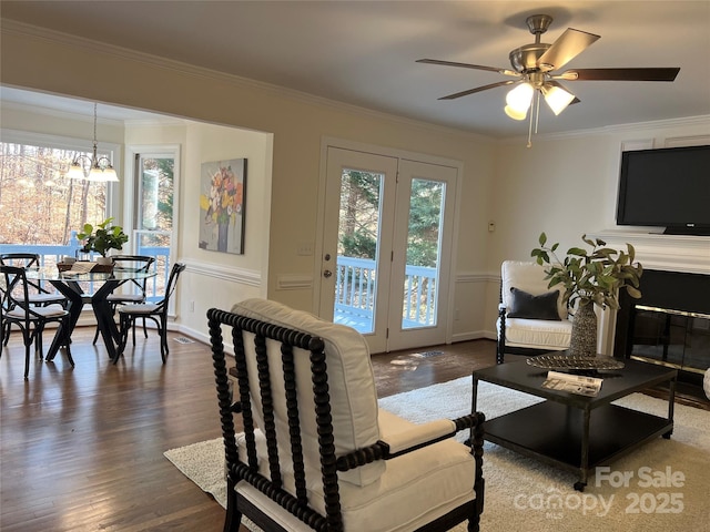 living room featuring hardwood / wood-style flooring, crown molding, and ceiling fan with notable chandelier