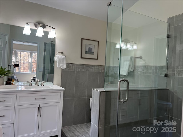 bathroom with vanity, tile walls, and walk in shower