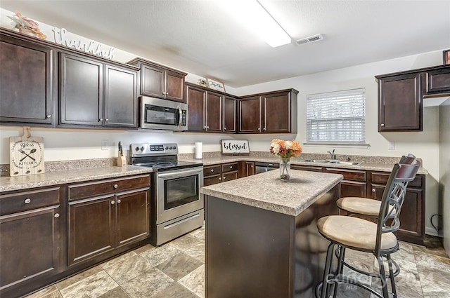 kitchen with a center island, sink, a breakfast bar area, dark brown cabinets, and stainless steel appliances