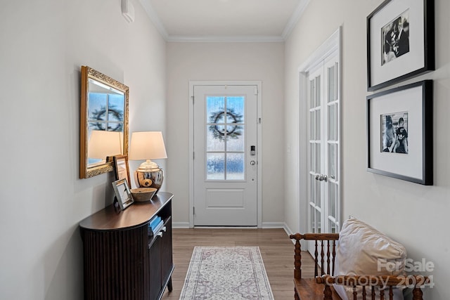 foyer featuring light wood-type flooring, ornamental molding, and french doors