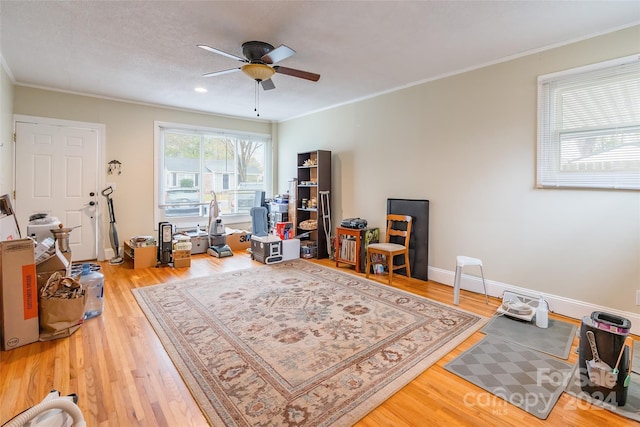 interior space with ceiling fan, wood-type flooring, and ornamental molding