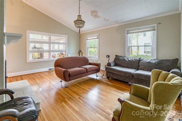 living room with light hardwood / wood-style flooring, vaulted ceiling, and ornamental molding