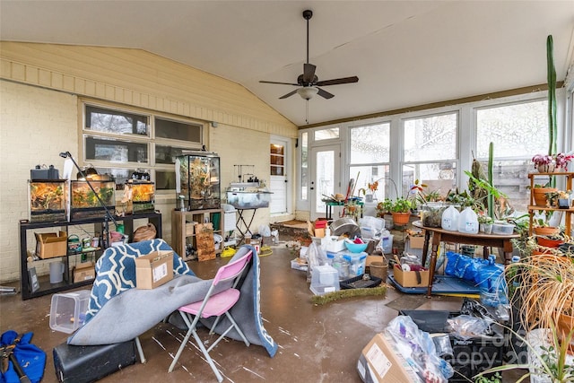 misc room with ceiling fan, lofted ceiling, brick wall, and concrete floors