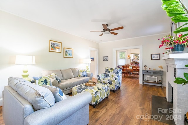 living room featuring dark hardwood / wood-style floors, ceiling fan, ornamental molding, and a fireplace