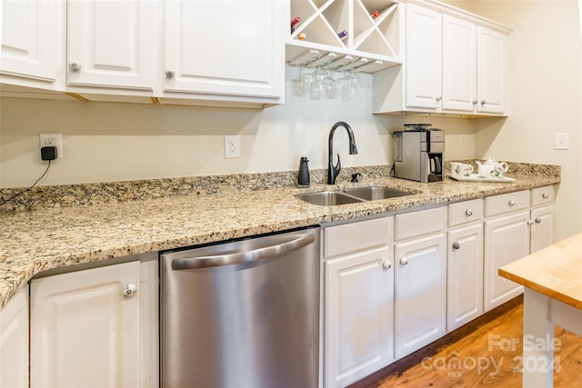 kitchen with light stone countertops, light wood-type flooring, sink, dishwasher, and white cabinetry