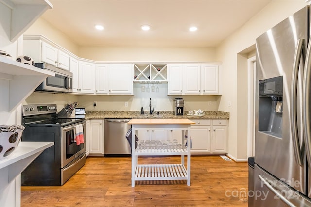 kitchen with white cabinets, stainless steel appliances, and light hardwood / wood-style flooring