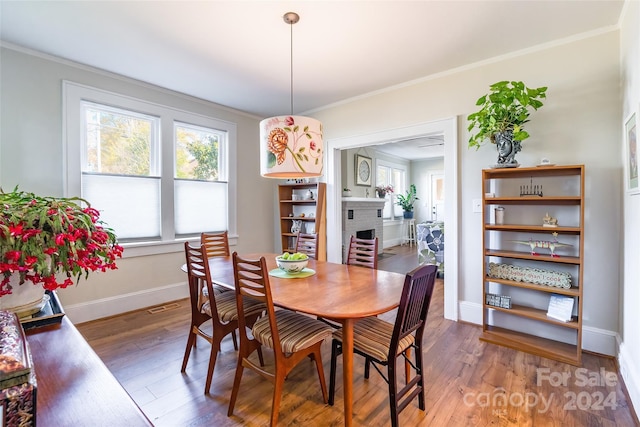 dining space featuring crown molding, a fireplace, and dark hardwood / wood-style floors