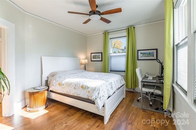 bedroom with ceiling fan, ornamental molding, and dark wood-type flooring