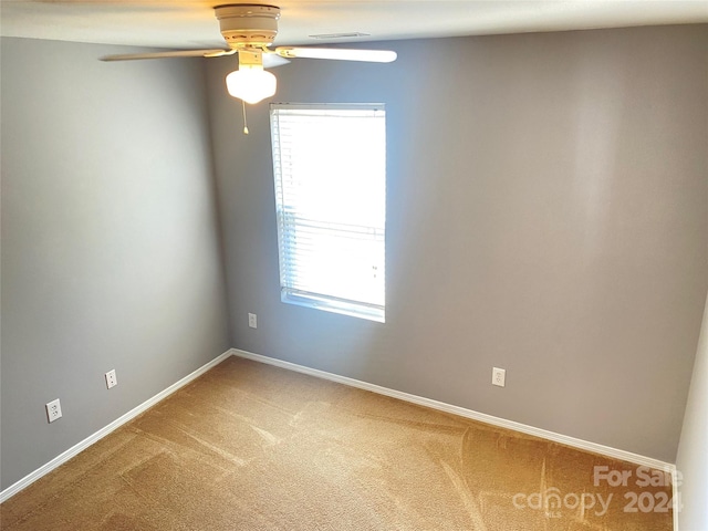 carpeted spare room featuring ceiling fan