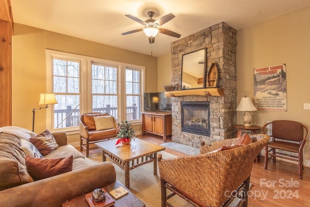 living room featuring ceiling fan, a fireplace, and light wood-type flooring