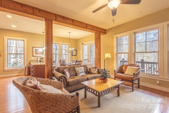 living room with ceiling fan with notable chandelier, light hardwood / wood-style floors, and sink