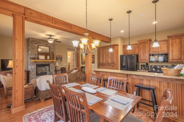 dining room with a fireplace, hardwood / wood-style floors, and ceiling fan with notable chandelier