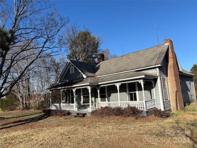 farmhouse-style home with a front lawn and covered porch