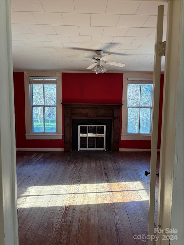 unfurnished living room with dark hardwood / wood-style flooring, a wealth of natural light, and ceiling fan