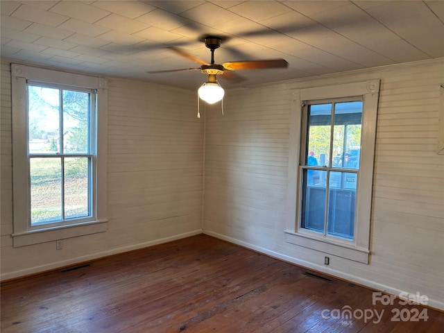 unfurnished room featuring a wealth of natural light, dark hardwood / wood-style flooring, and ceiling fan