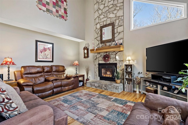 living room featuring a fireplace, hardwood / wood-style floors, and a towering ceiling