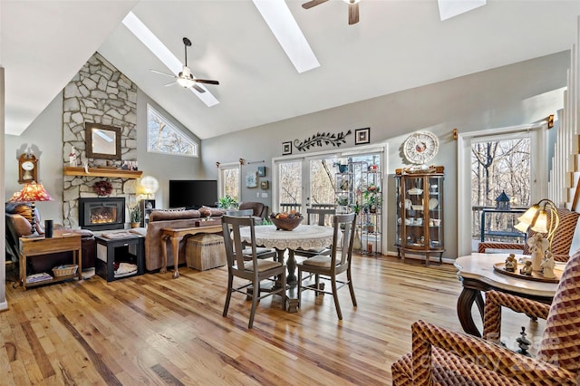 dining space with a skylight, ceiling fan, high vaulted ceiling, and light hardwood / wood-style floors