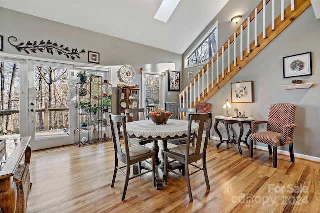 dining area with light hardwood / wood-style floors, a wealth of natural light, and a skylight