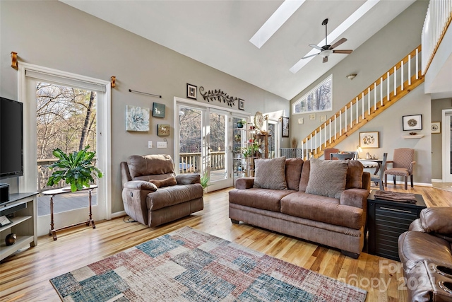 living room featuring light wood-type flooring, a skylight, high vaulted ceiling, and ceiling fan