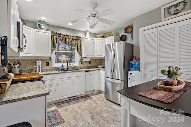 kitchen with stainless steel fridge, white cabinetry, ceiling fan, and sink