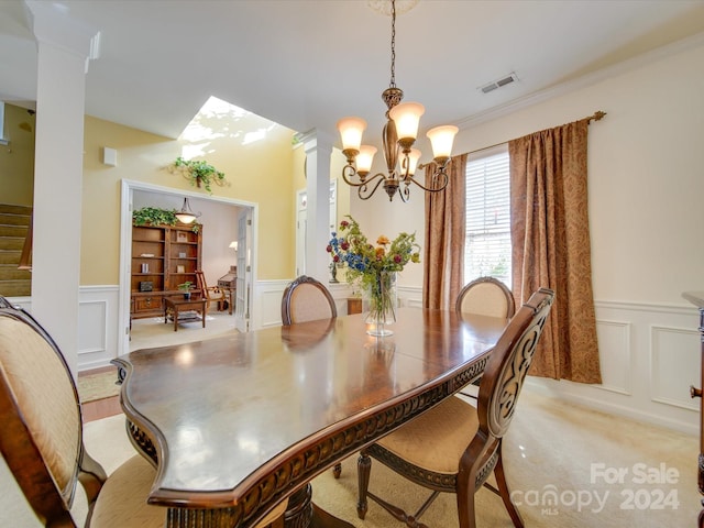 dining area with crown molding, decorative columns, light carpet, and a chandelier