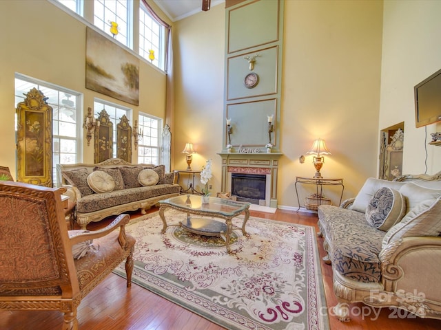 living room featuring a towering ceiling, light hardwood / wood-style flooring, a wealth of natural light, and crown molding