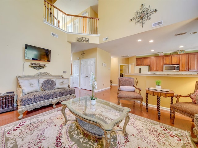 living room featuring a towering ceiling and light hardwood / wood-style flooring